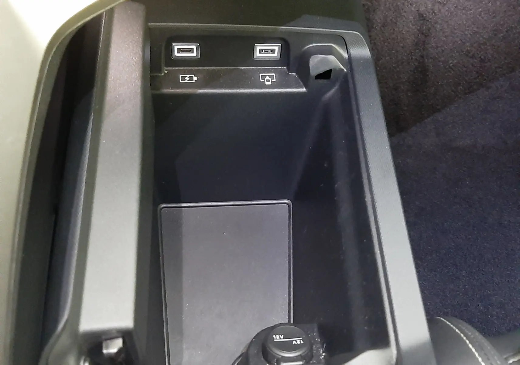Gros plan intérieur sur la console centrale noire du Peugeot 3008 2025 avec ports USB et prise 12V visibles.