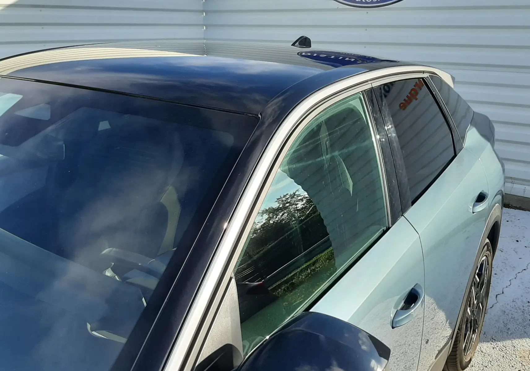 Vue 3/4 avant droit du Peugeot 3008 2025 bleu Ingaro avec toit et rétroviseur noir brillant, stationné devant un mur blanc.