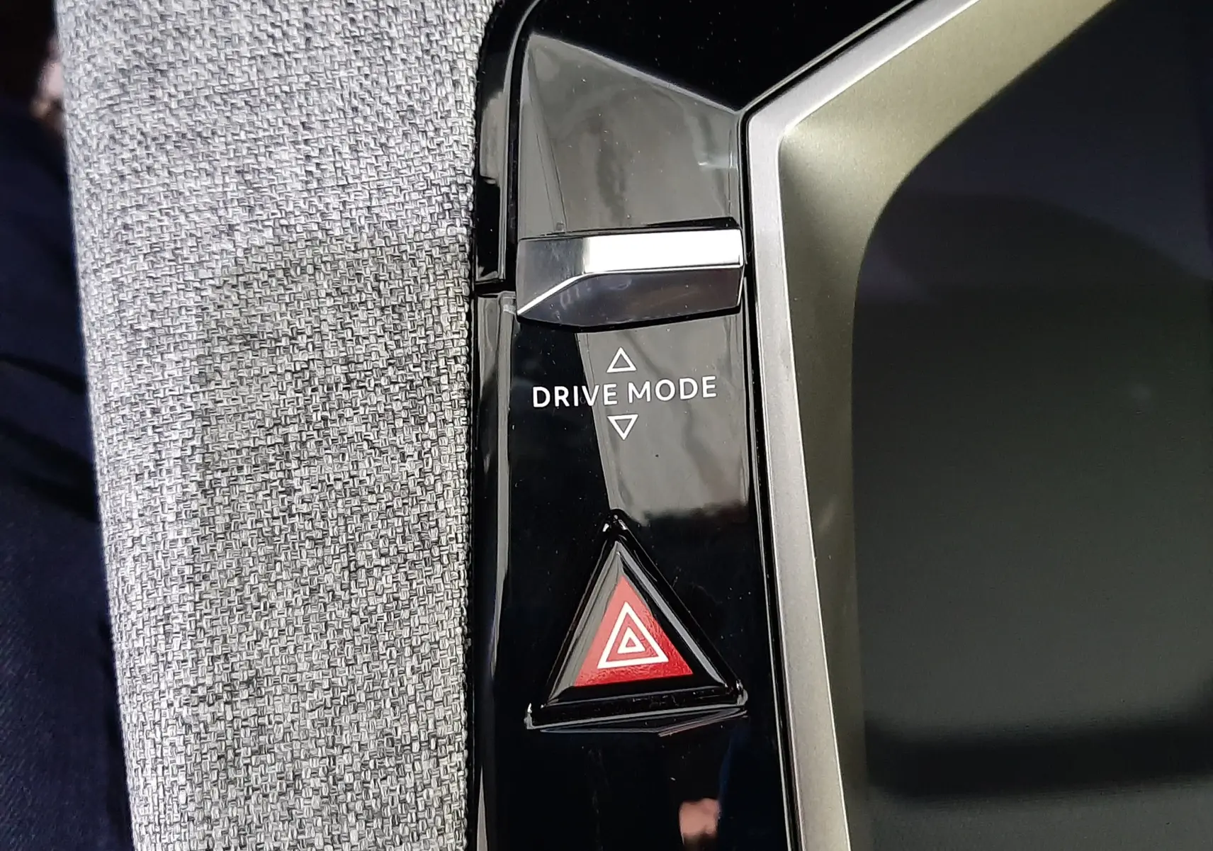 Détail de la console centrale noire du Peugeot 3008 1.2 Hybrid 145ch GT avec bouton Drive Mode et alerte triangle rouge.