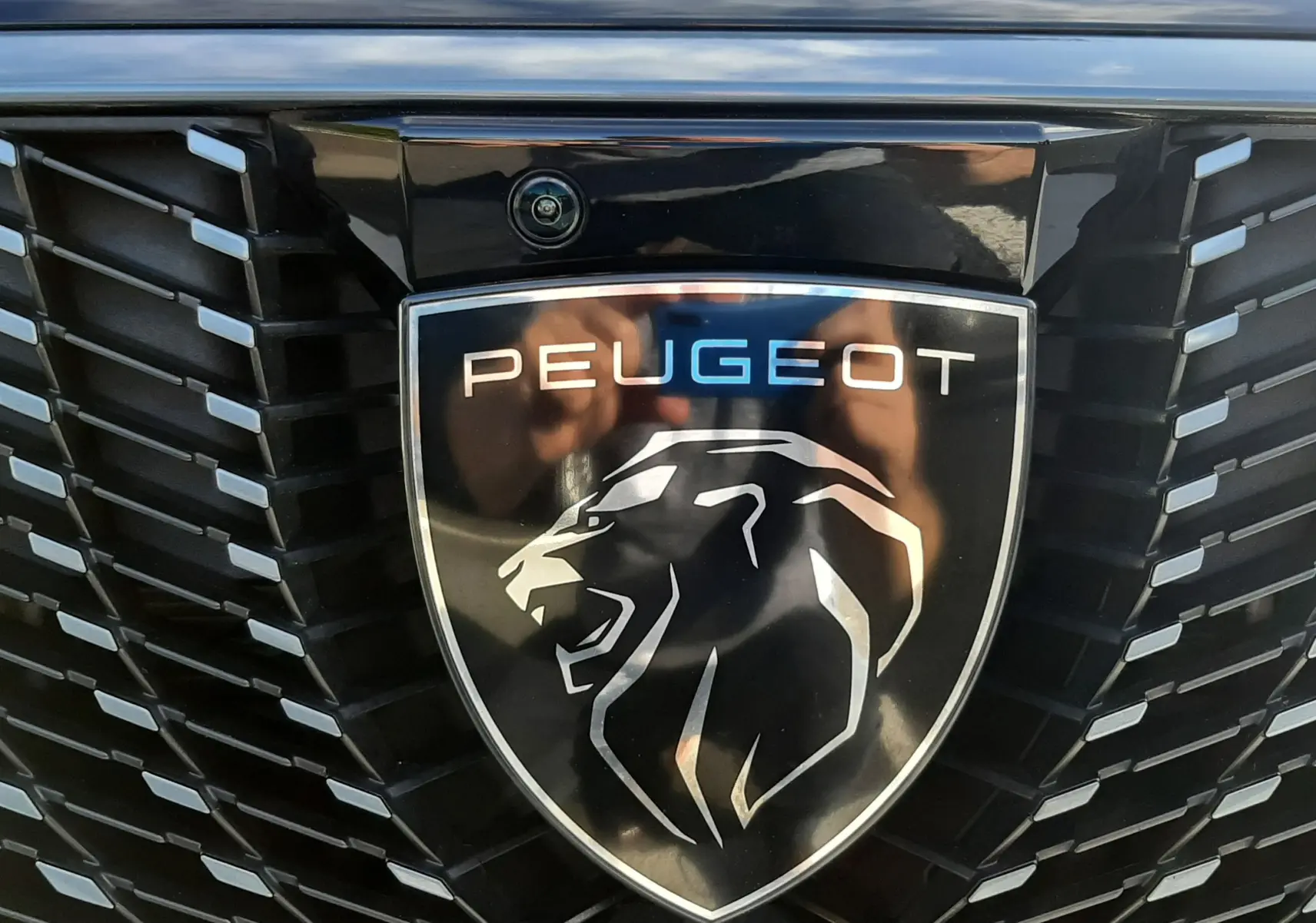 Gros plan sur la calandre noire brillante du Peugeot 3008 2025 avec logo lion et inscription 3008 en relief.