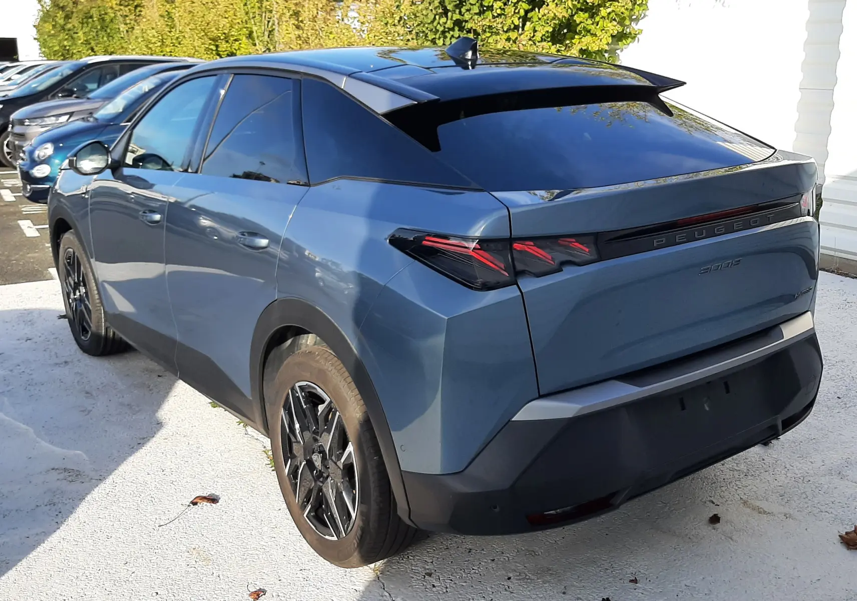 Vue 3/4 arrière gauche d'un Peugeot 3008 bleu Ingaro avec toit noir et feux arrière LED distinctifs.