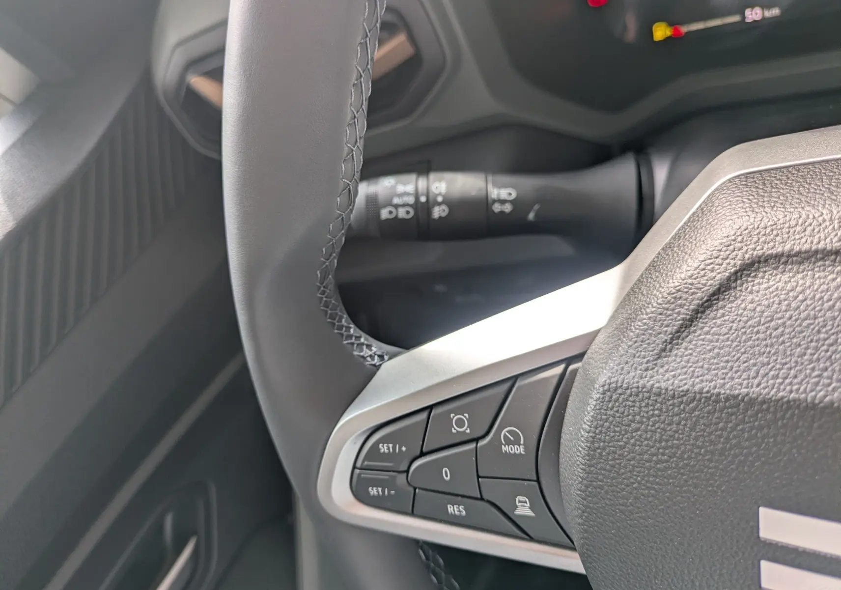 Gros plan sur le volant multifonction du Dacia Bigster Hybrid 155 Extreme, avec commandes intégrées et tableau de bord partiel.