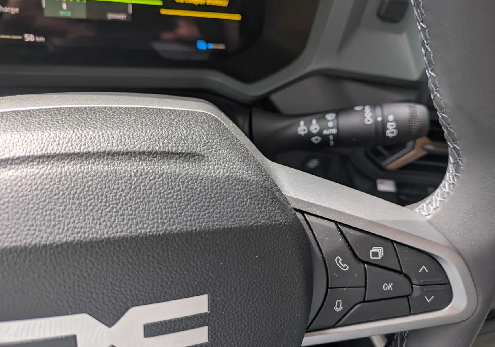 Gros plan sur le volant du Dacia Bigster Hybrid 155 Extreme avec commandes intégrées, intérieur gris et écran digital partiel visible.