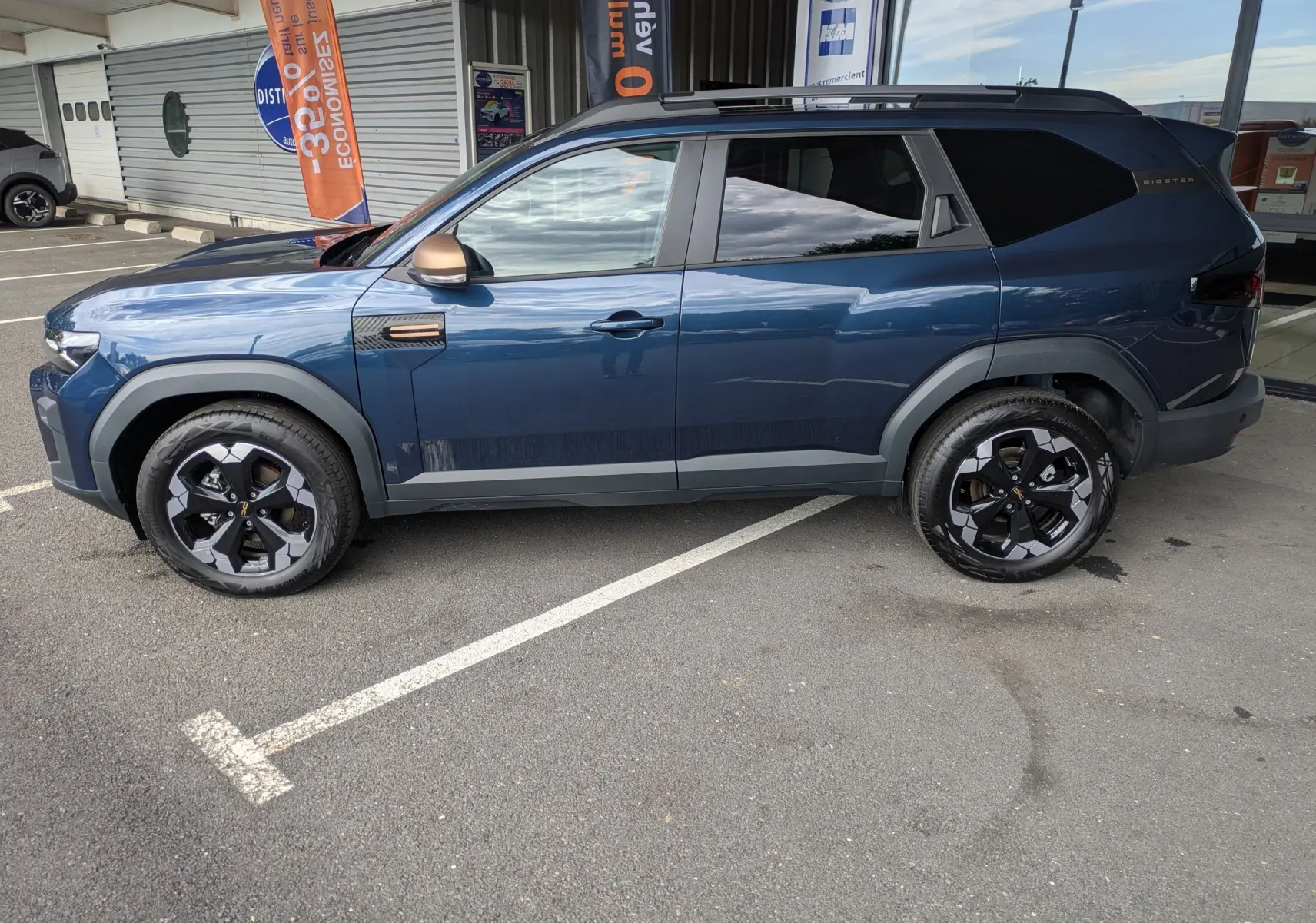 Vue latérale gauche du Dacia Bigster Hybrid 155 Extreme bleu indigo avec jantes diamantées et rétroviseurs bronze.