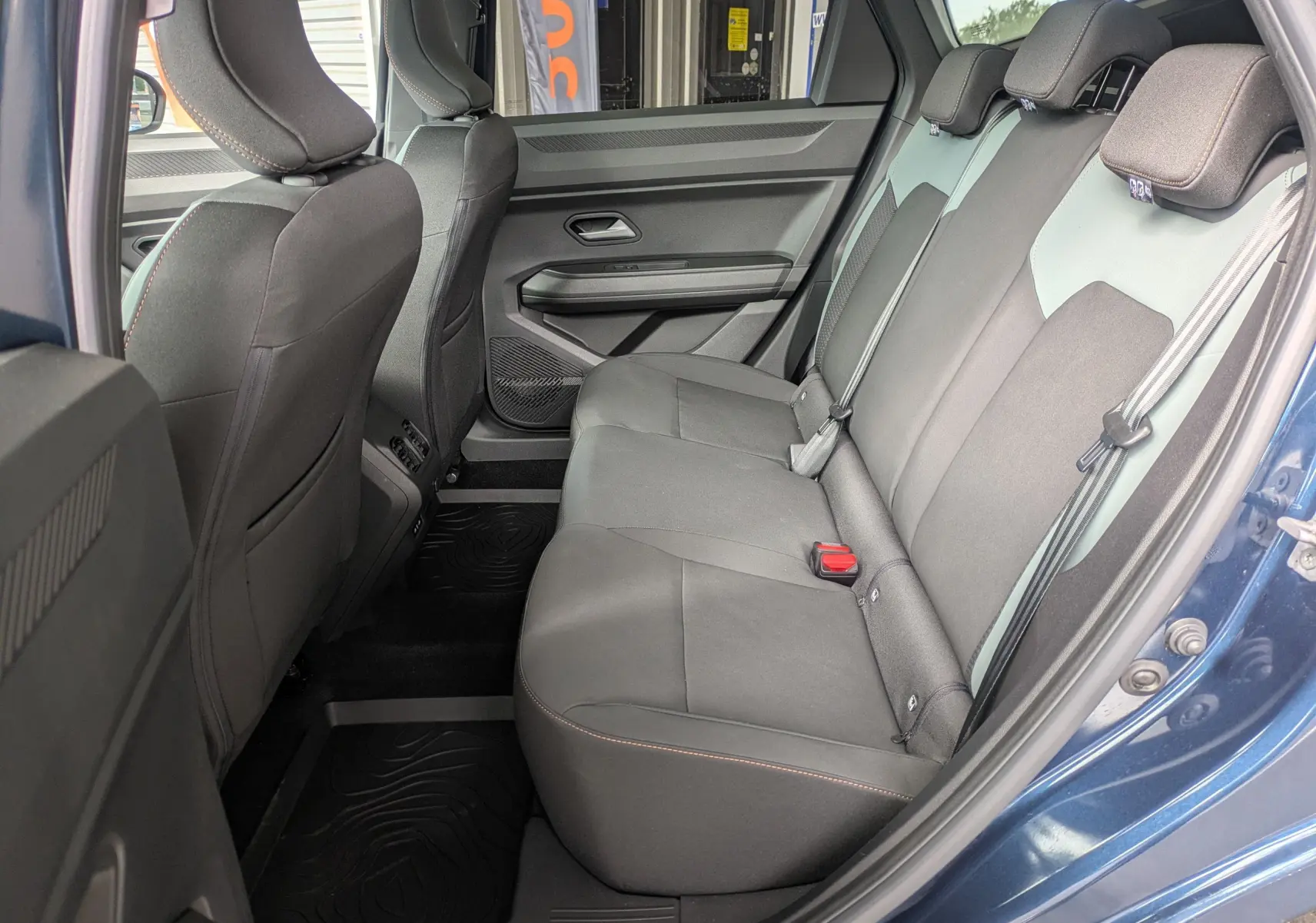 Vue intérieure côté droit des sièges arrière noirs du Dacia Bigster Hybrid 155 Extreme bleu indigo avec portières ouvertes.