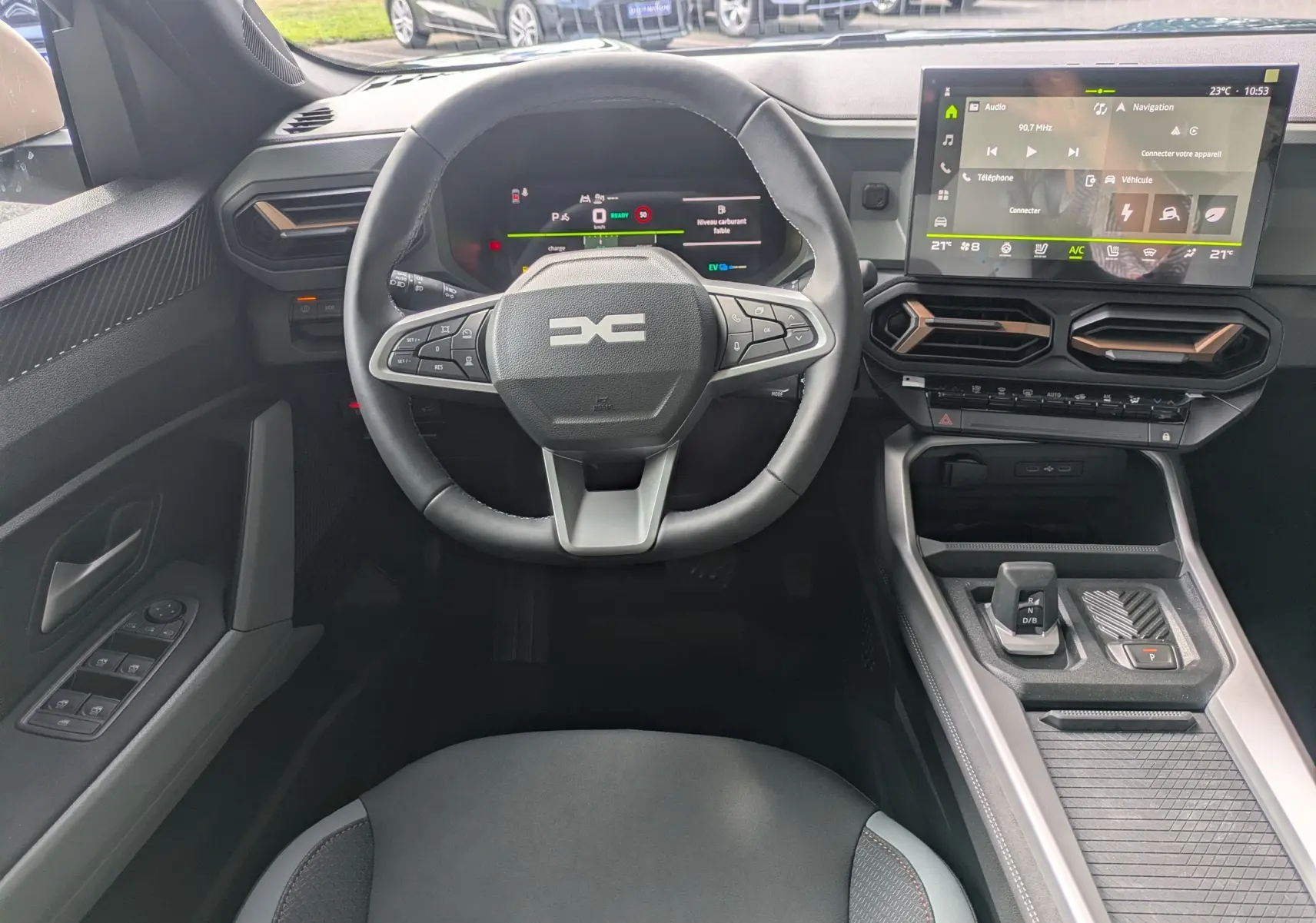 Vue intérieure centrée sur le volant et tableau de bord du Dacia Bigster Hybrid 155, avec écran tactile et console moderne.