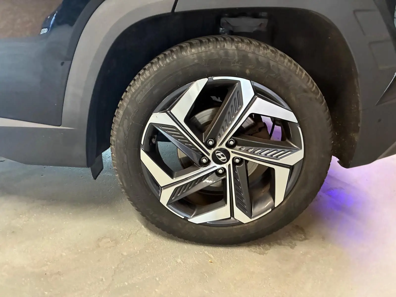 Gros plan sur la roue avant gauche du Hyundai Tucson noir 2022, mettant en valeur la jante alliage au design moderne.