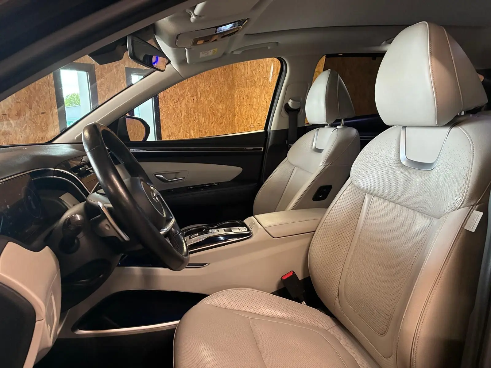 Vue intérieure côté conducteur du Hyundai Tucson 2022, sièges en cuir beige et tableau de bord noir élégant.