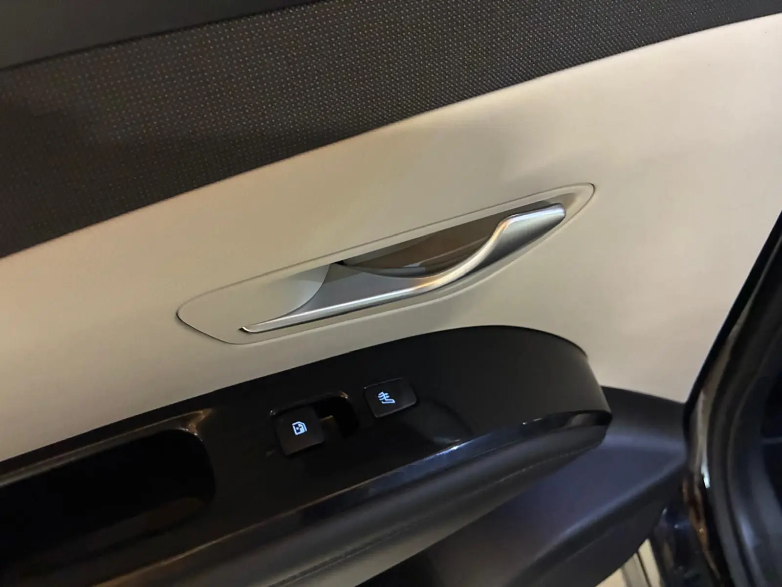 Gros plan sur la poignée intérieure et les commandes de porte côté gauche du Hyundai Tucson noir, finition Executive 2022.