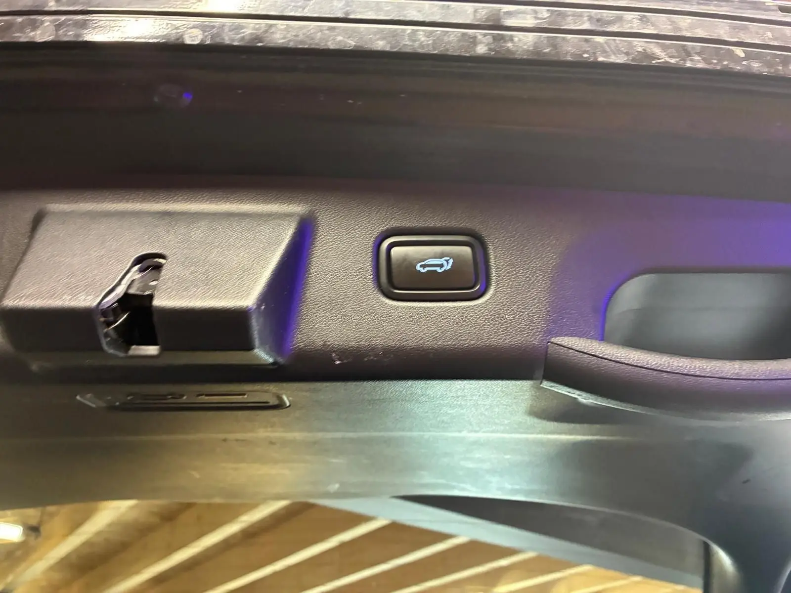 Détail du bouton d'ouverture électrique du coffre sur la porte arrière d'un Hyundai Tucson noir 2022.