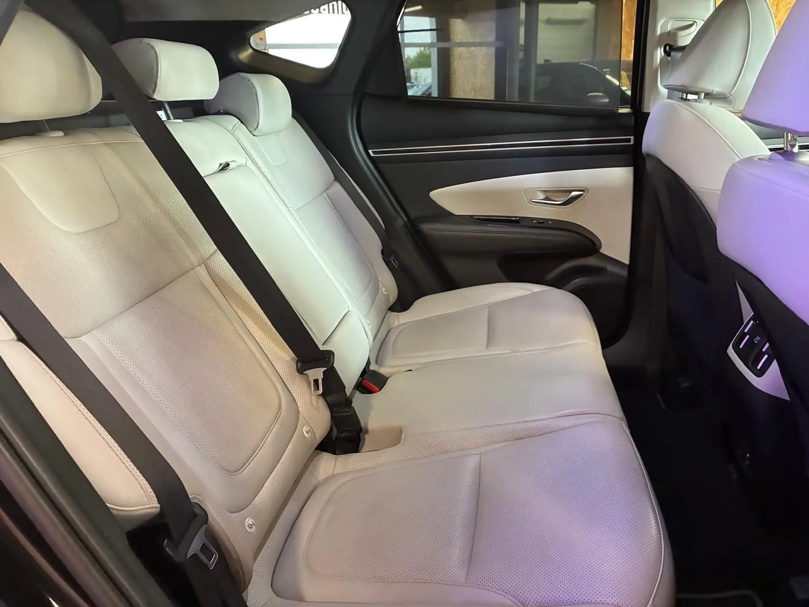 Vue intérieure côté droit des sièges arrière en cuir beige du Hyundai Tucson 2022, avec ceintures de sécurité visibles.