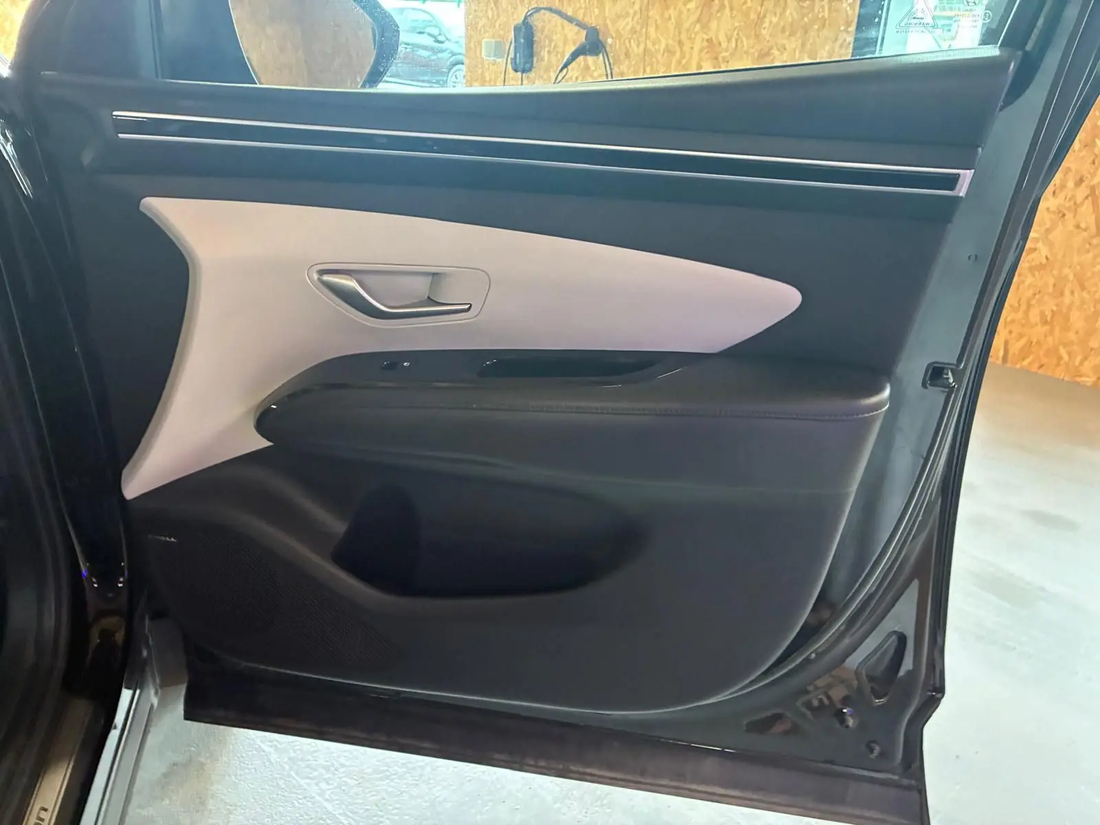 Vue intérieure de la porte avant droite noire du Hyundai Tucson 2022 avec insert clair et poignée argentée.