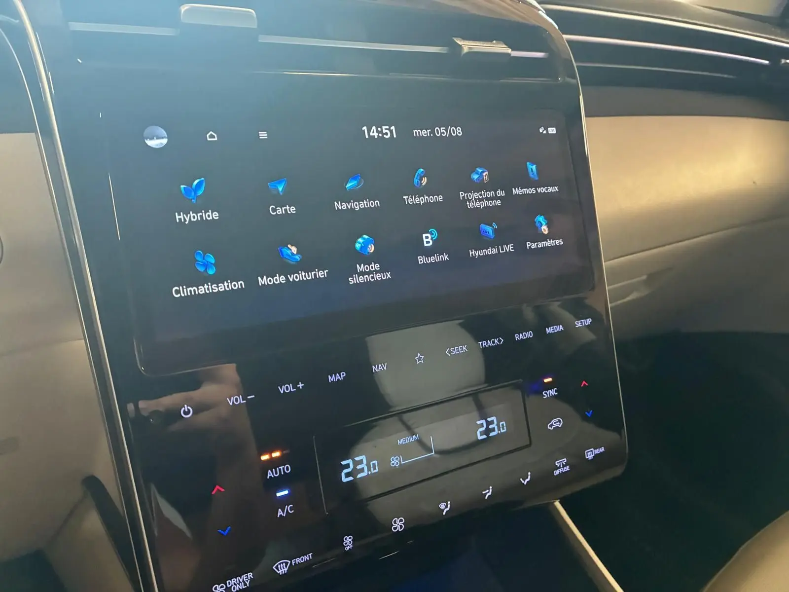 Vue rapprochée de l'écran tactile central du Hyundai Tucson noir 2022, affichant la climatisation et la navigation.