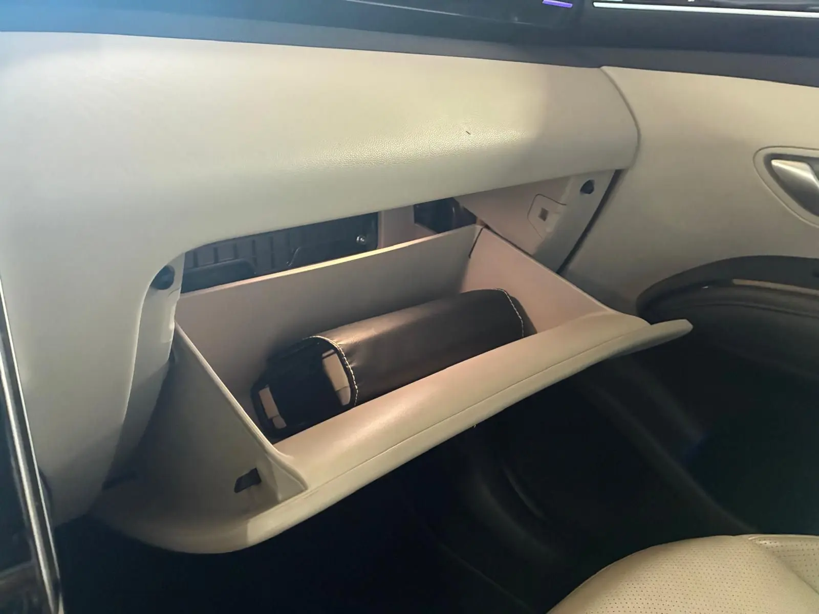 Vue intérieure côté passager du Hyundai Tucson 2022 hybride, boîte auto, avec boîte à gants ouverte et pochette noire visible.