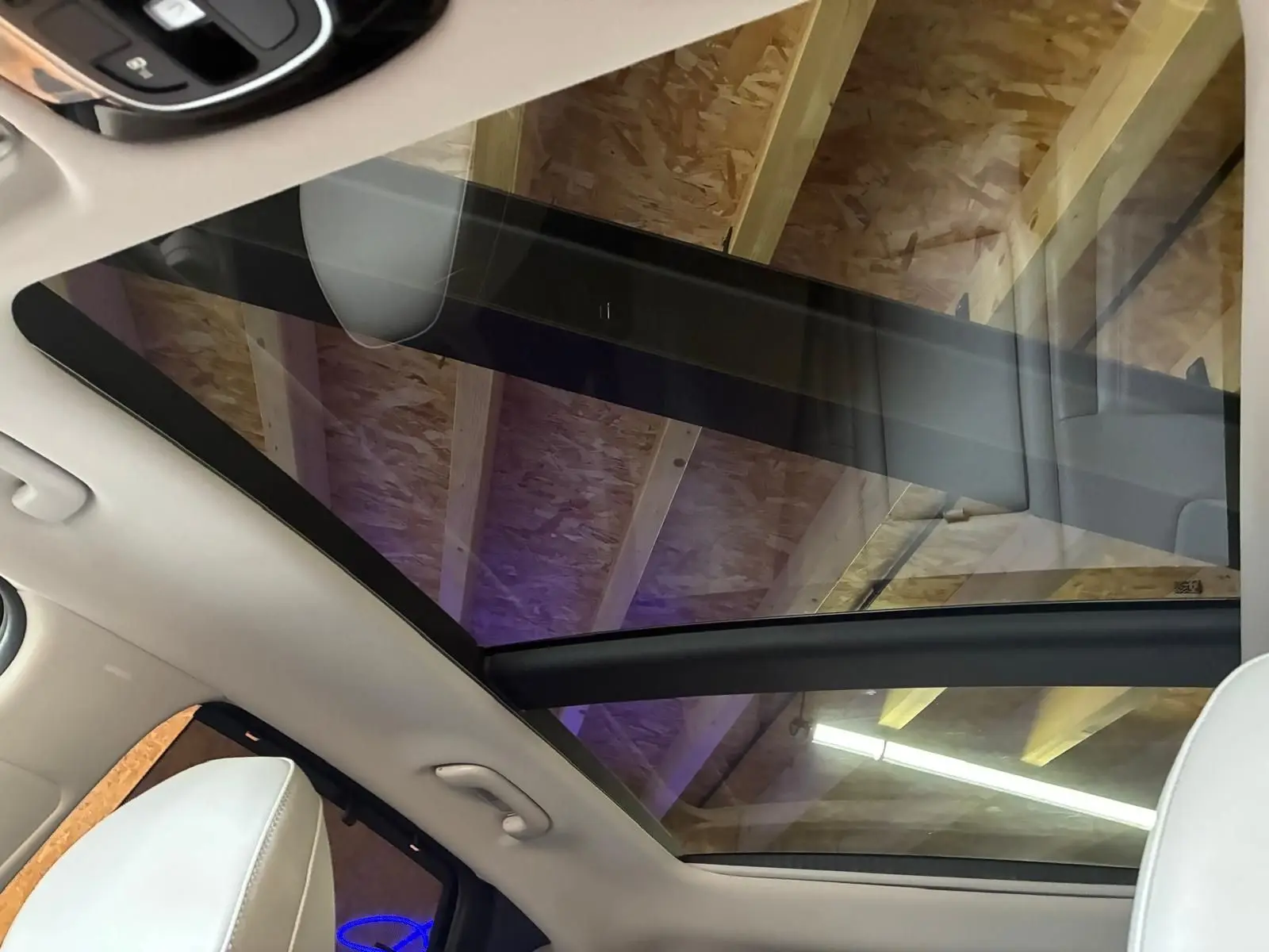 Vue intérieure du toit panoramique en verre du Hyundai Tucson noir, avec sièges cuir beige visibles au premier plan.