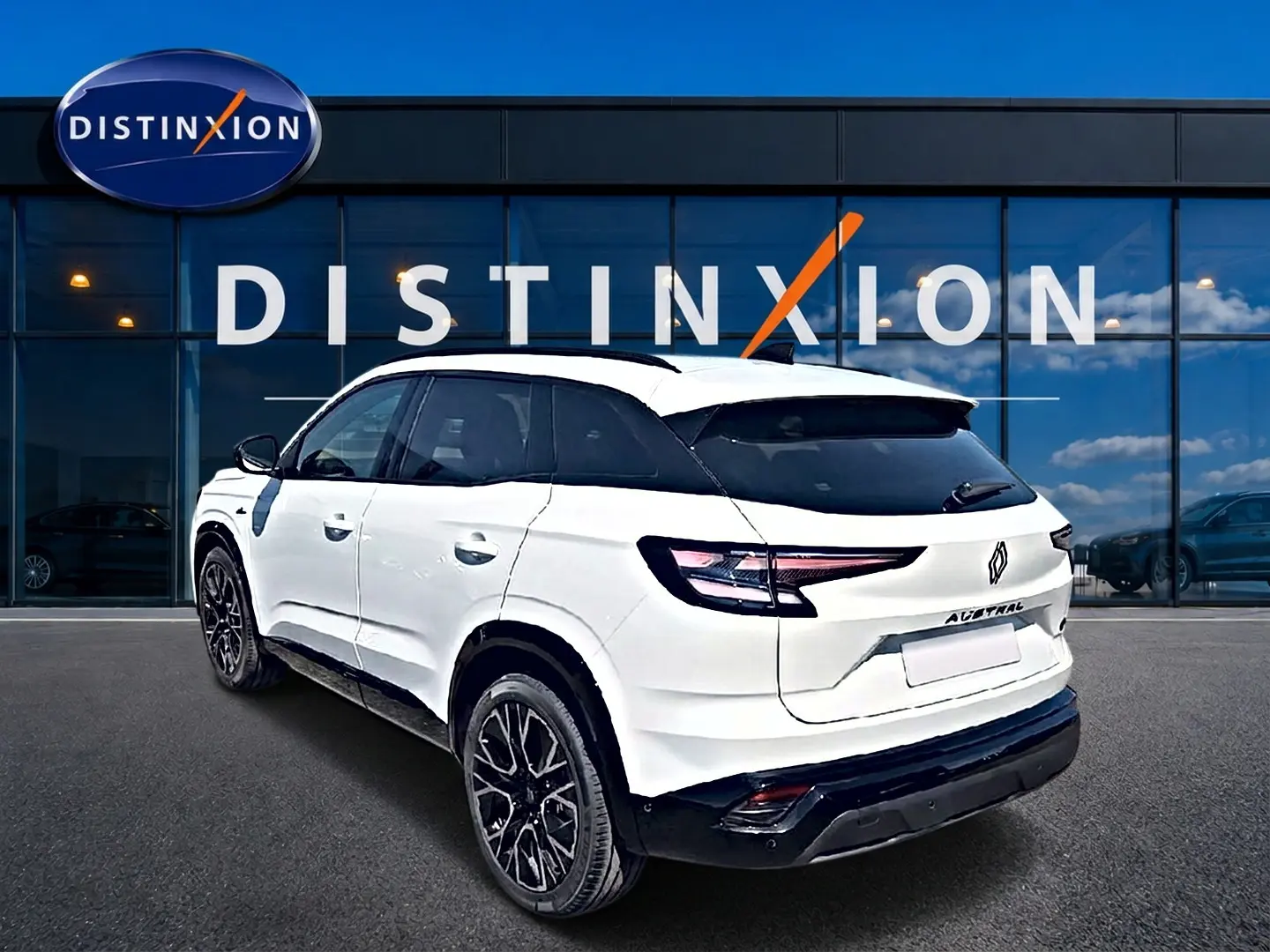 Vue 3/4 arrière droite du Renault Austral blanc nacré avec jantes noires devant une vitrine Distinxion.