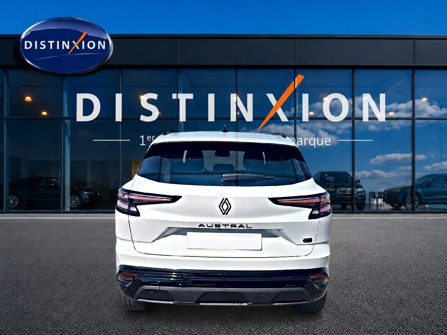 Vue arrière d'un Renault Austral blanc nacré garé devant une vitrine avec logo Distinxion.