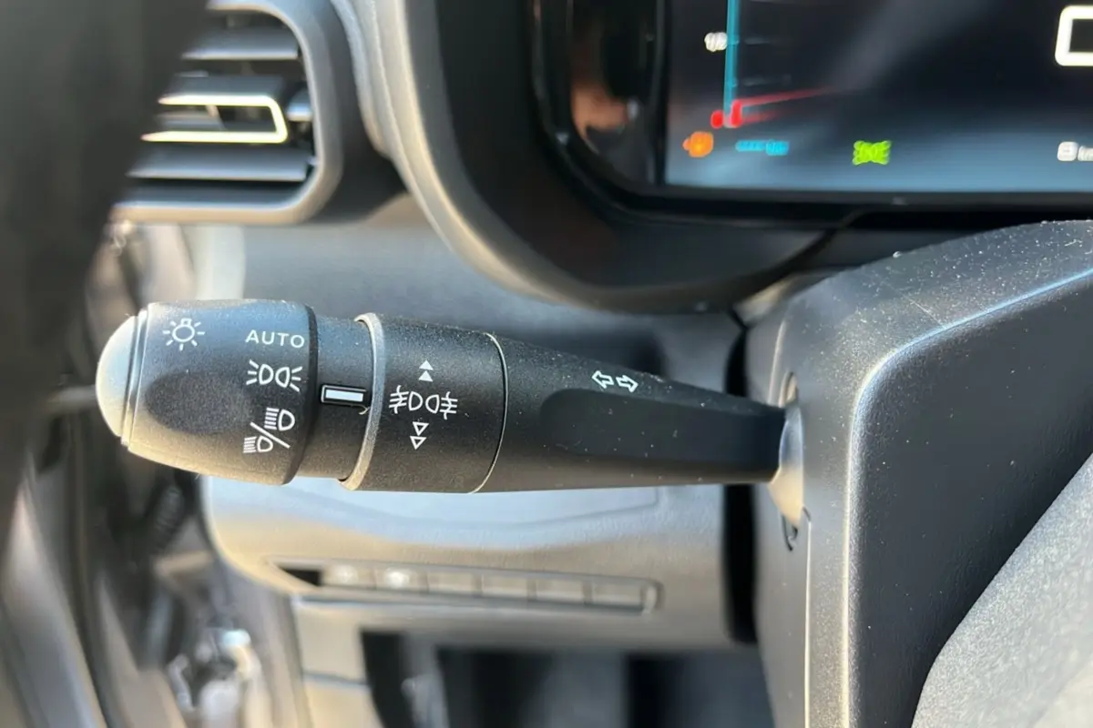 Gros plan sur la commande des feux et clignotants du tableau de bord du Citroën Berlingo 2025, intérieur noir.