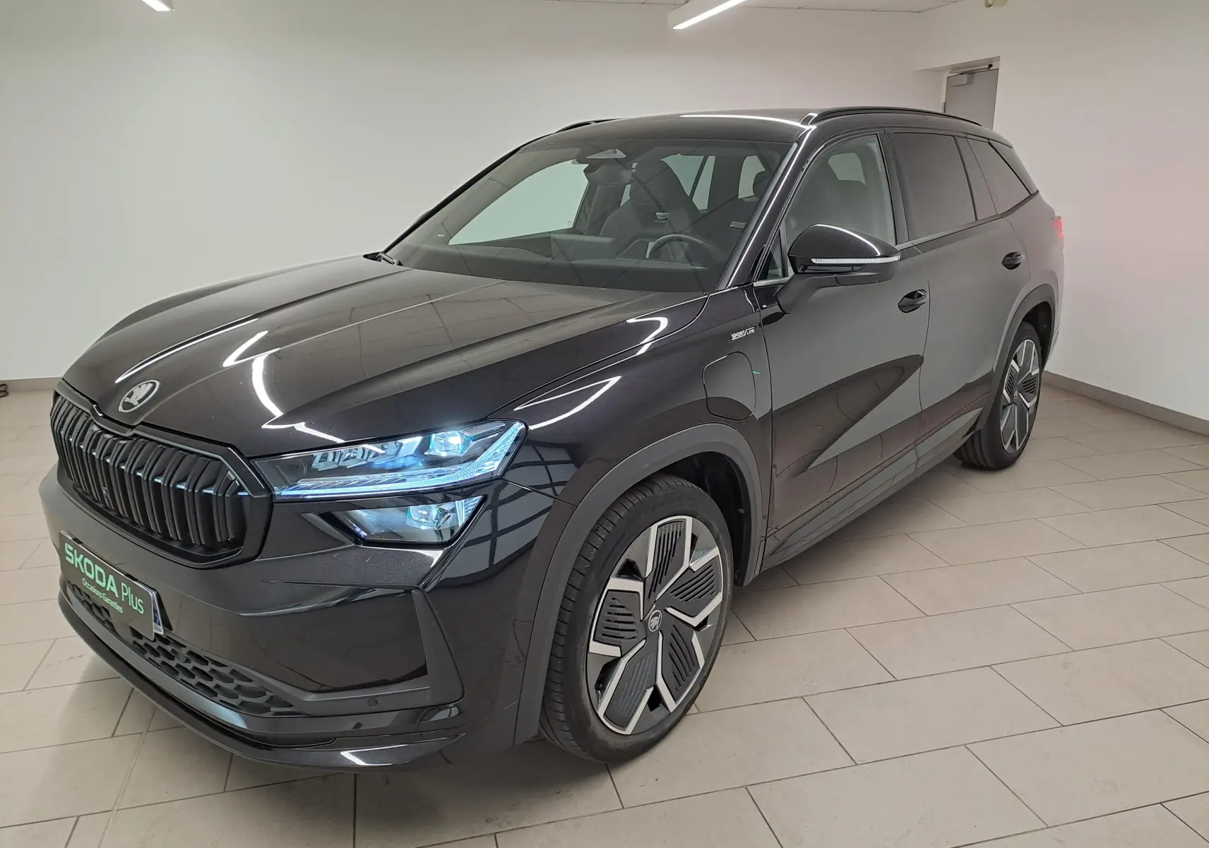 Vue 3/4 avant du Skoda Kodiaq noir Magic nacré avec calandre noire et jantes alliage 20 pouces en intérieur showroom.