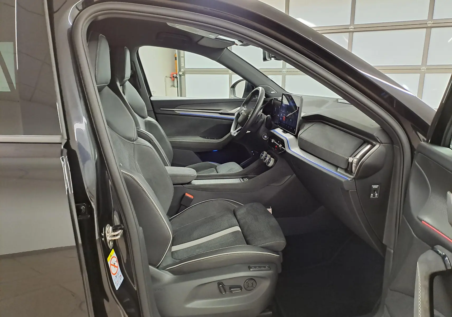 Intérieur côté conducteur du Skoda Kodiaq noir Magic nacré, sièges sport, tableau de bord moderne avec écran tactile.