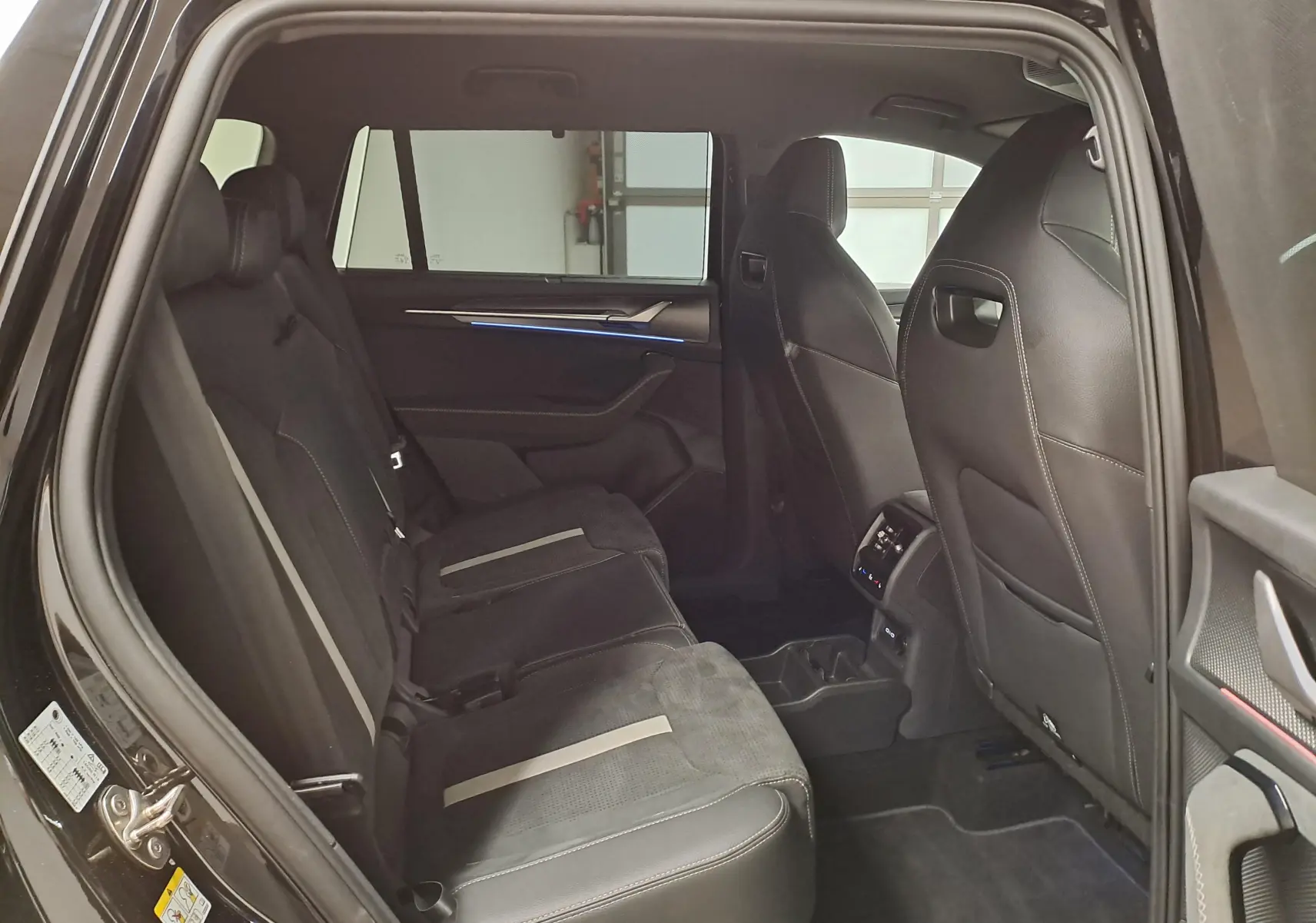 Vue intérieure côté gauche des sièges arrière noirs avec surpiqûres claires du Skoda Kodiaq 2025 finition Sportline.