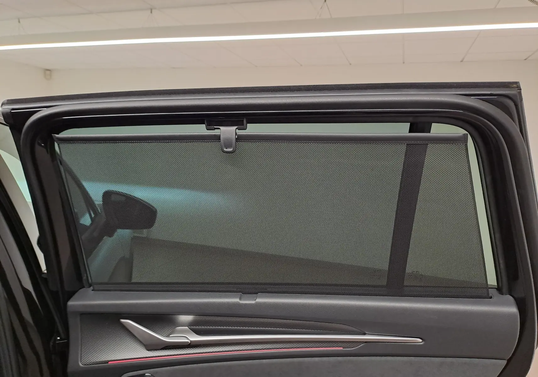 Vue intérieure de la porte arrière gauche d’un Skoda Kodiaq noir Magic Nacré avec pare-soleil intégré.