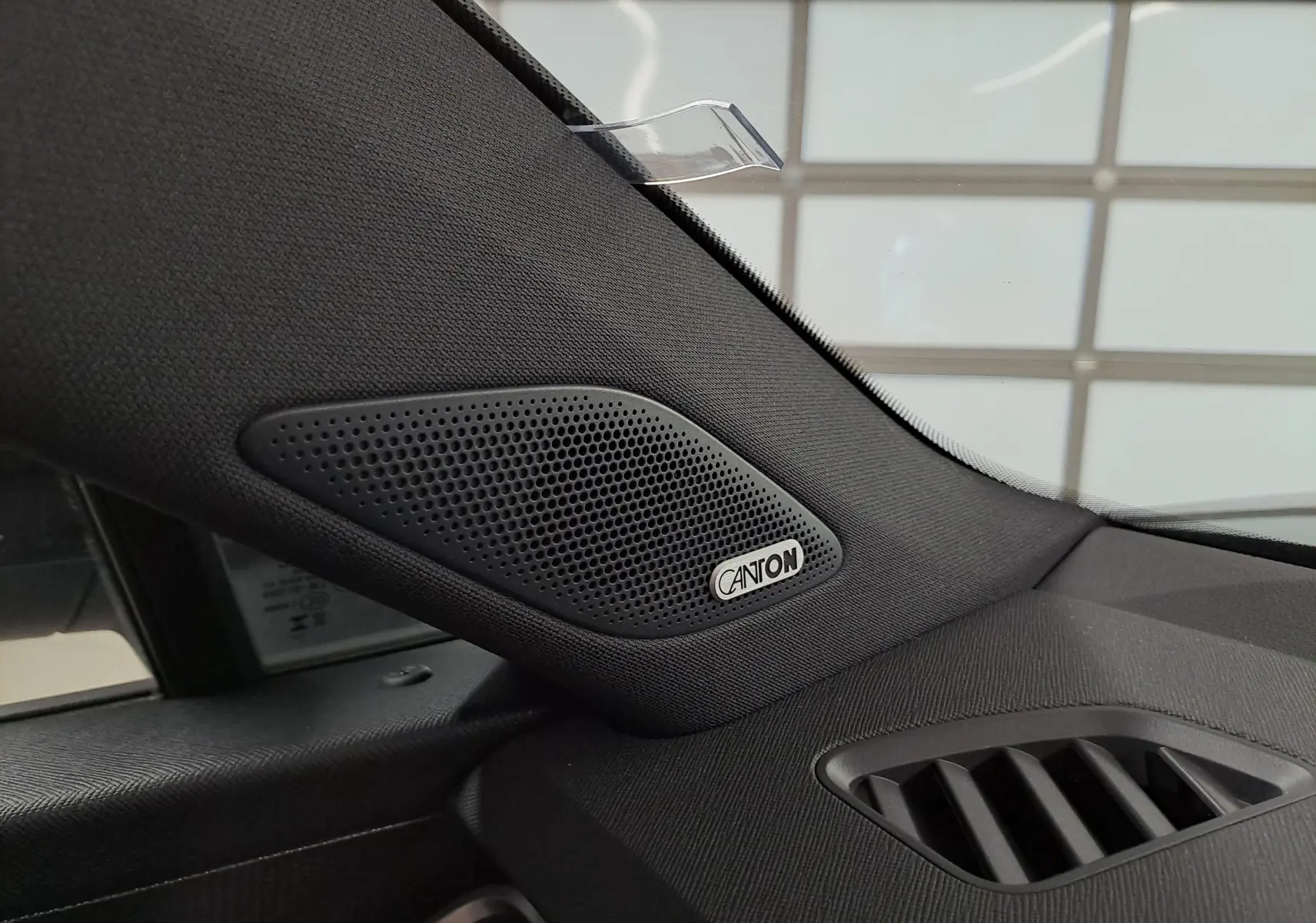 Gros plan sur le haut de la planche de bord côté gauche du Skoda Kodiaq noir, avec haut-parleur Canton intégré.