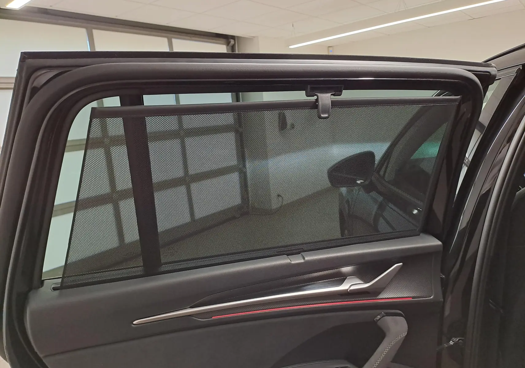 Vue intérieure de la porte arrière gauche d’un Skoda Kodiaq noir Magic nacré avec pare-soleil intégré et garniture noire.