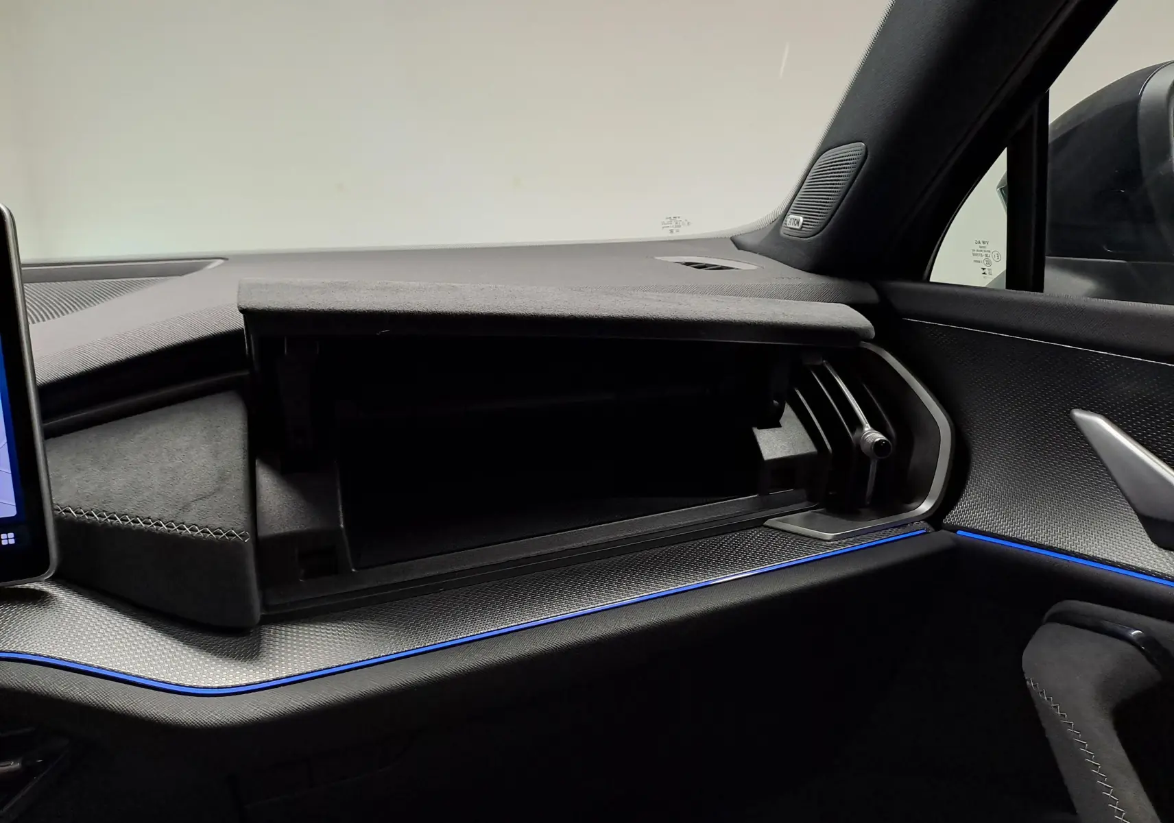 Intérieur du Skoda Kodiaq 2025, vue côté passager sur boîte à gants ouverte et éclairage d'ambiance bleu.
