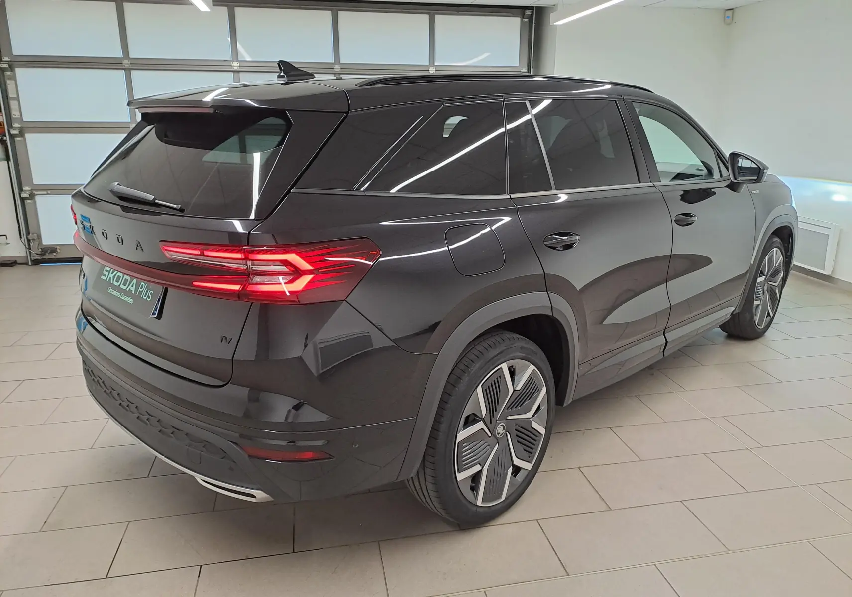 Vue 3/4 arrière droite d’un Skoda Kodiaq noir Magic nacré avec jantes alliage 20'' et feux arrière LED allumés.