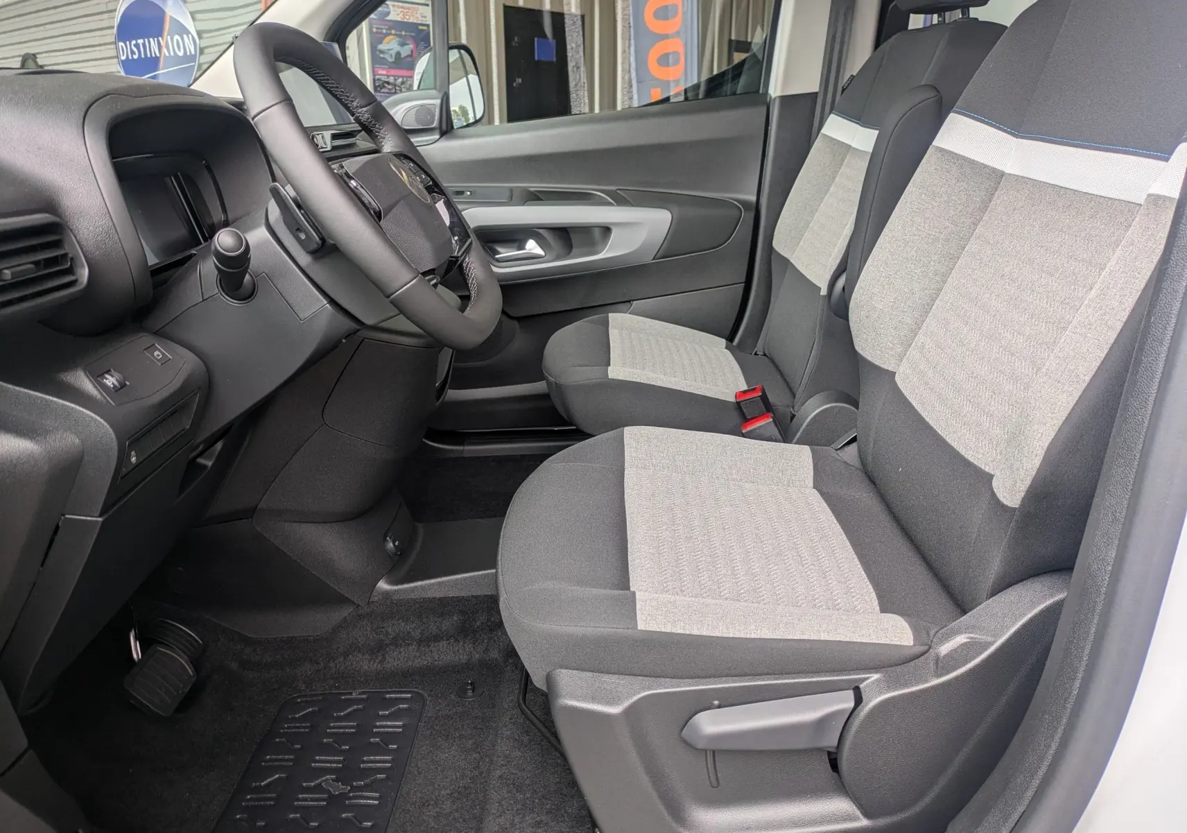 Vue intérieure côté conducteur du Citroën Berlingo blanc 2025, montrant les sièges avant bicolores et le tableau de bord.