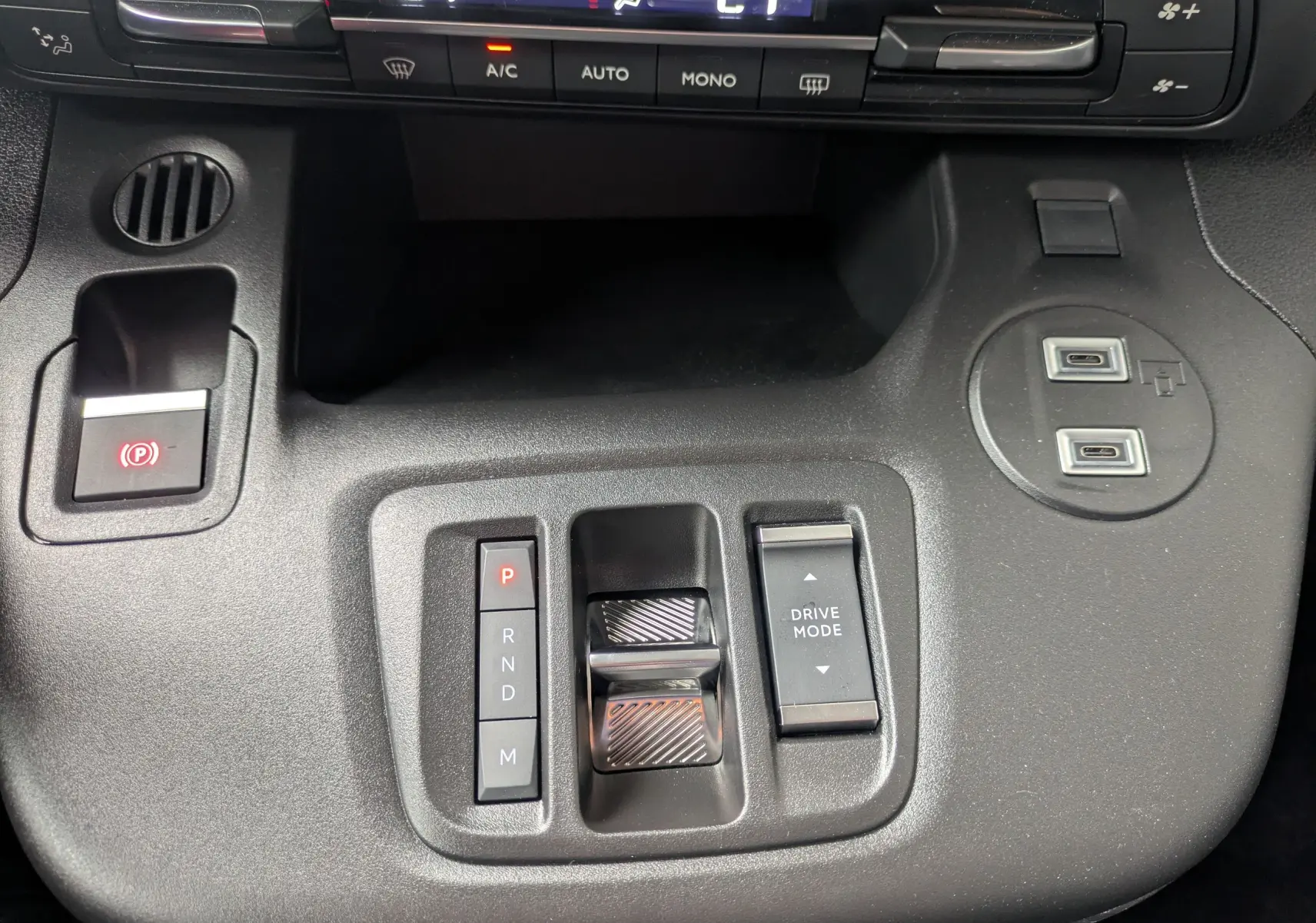 Vue rapprochée de la console centrale noire du Citroën Berlingo 2025, avec commandes de boîte auto et ports USB.
