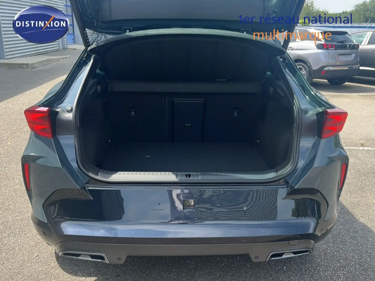 Vue arrière du coffre ouvert d'une CUPRA Formentor bleu Fjord métal, mettant en valeur l'espace de chargement.