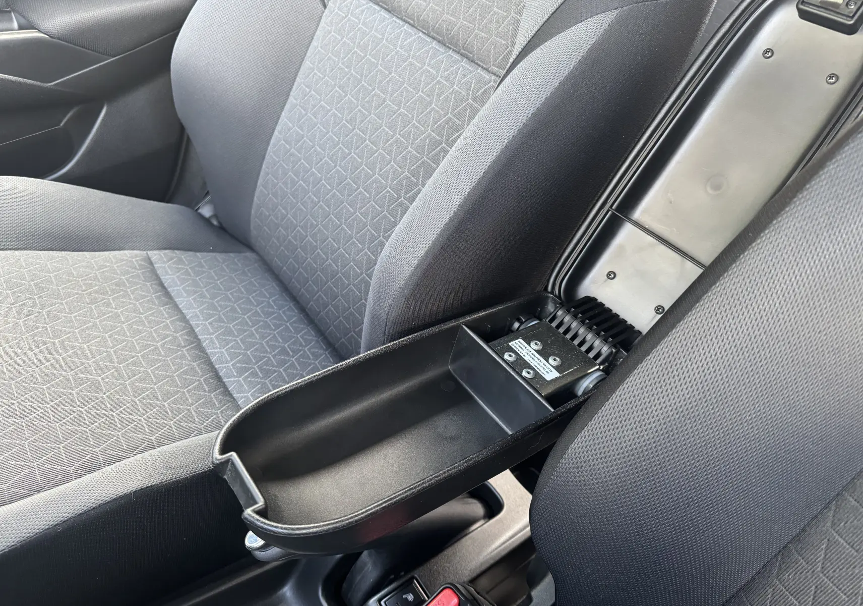 Vue rapprochée de l'accoudoir central ouvert entre les sièges avant gris de la Suzuki Swift 1.2 Pack Hybrid 2024.