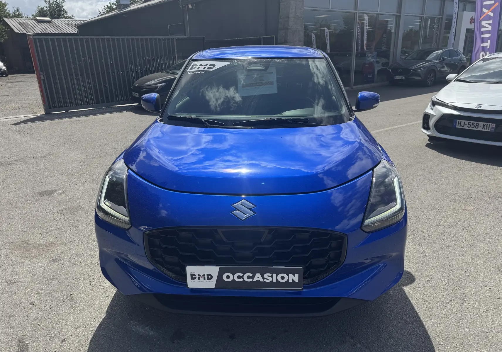 Vue avant d'une Suzuki Swift 1.2 Pack Hybrid bleu vif, avec calandre noire et badge Suzuki bien visible.