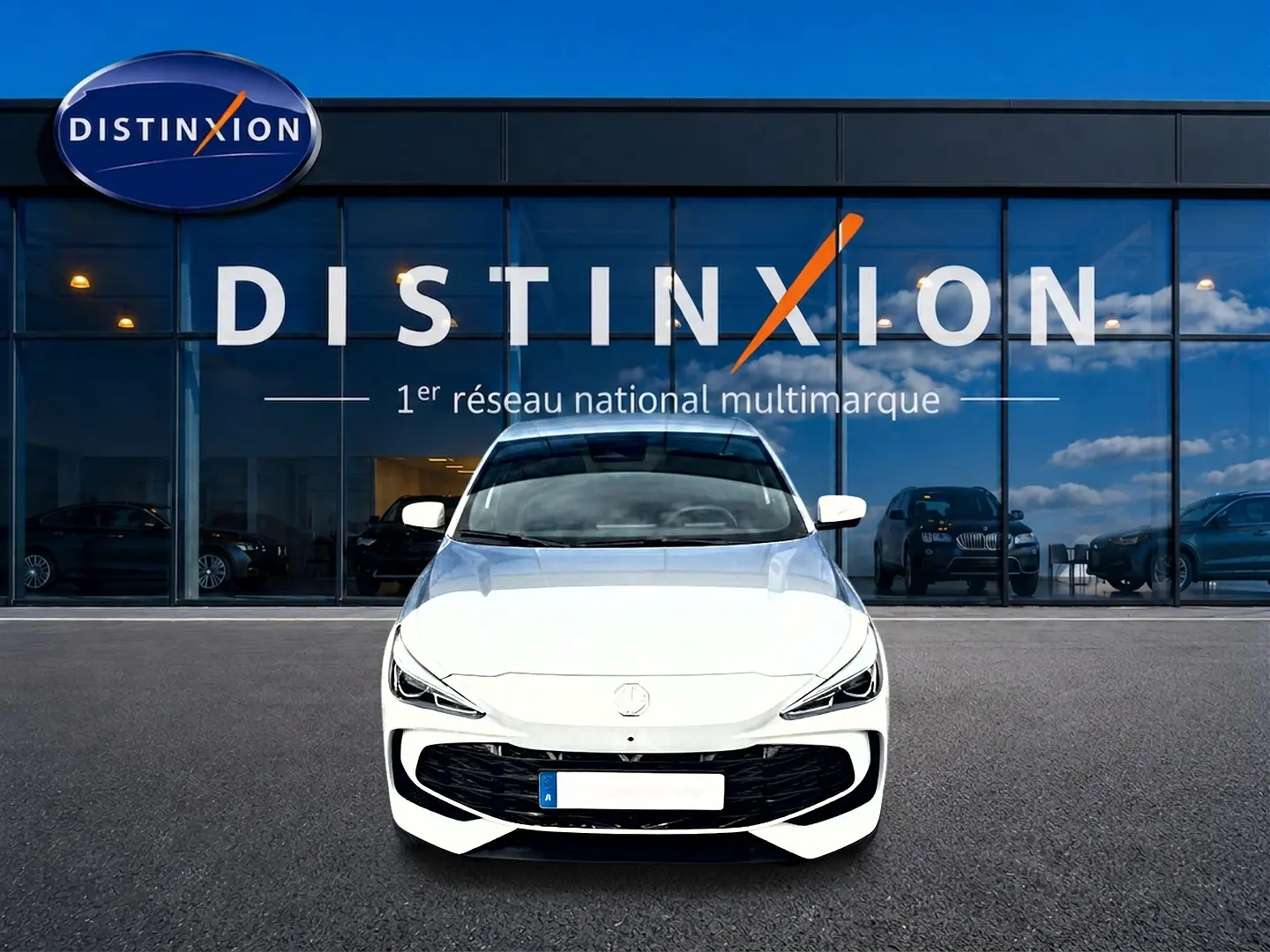 Vue frontale d'une MG3 1.5 hybrid 195 luxury blanche, avec calandre noire et phares LED fins, devant une vitrine Distinxion.
