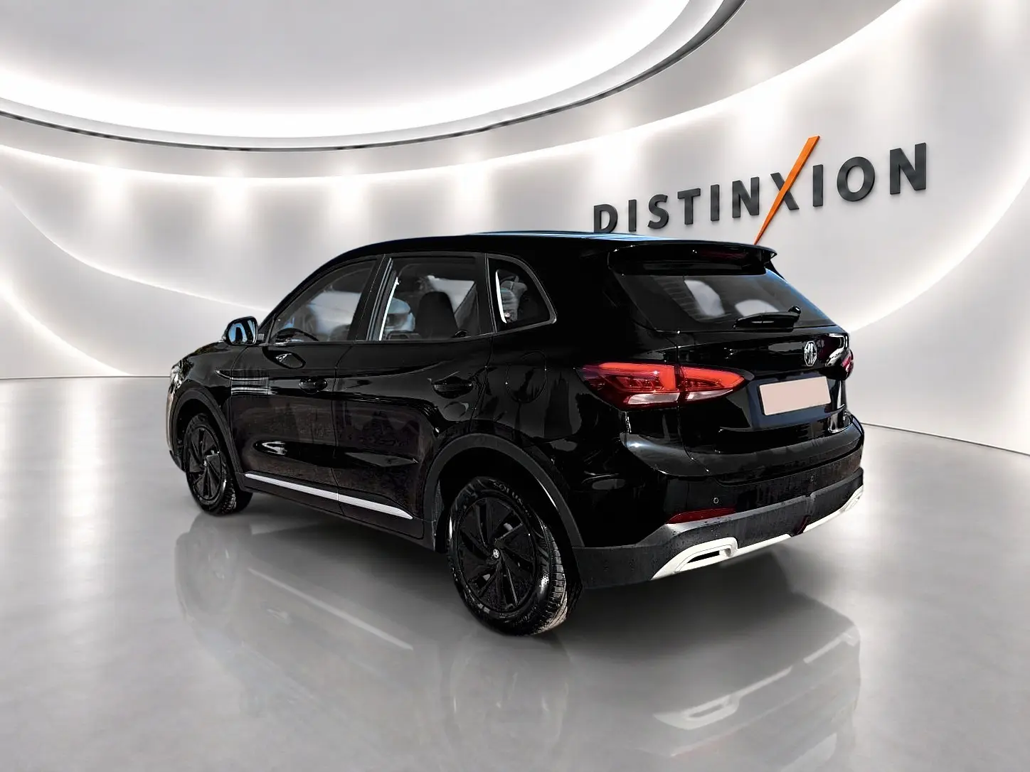 Vue 3/4 arrière droite du MG ZS 1.5 hybrid noir, avec feux arrière LED et becquet arrière en showroom lumineux.