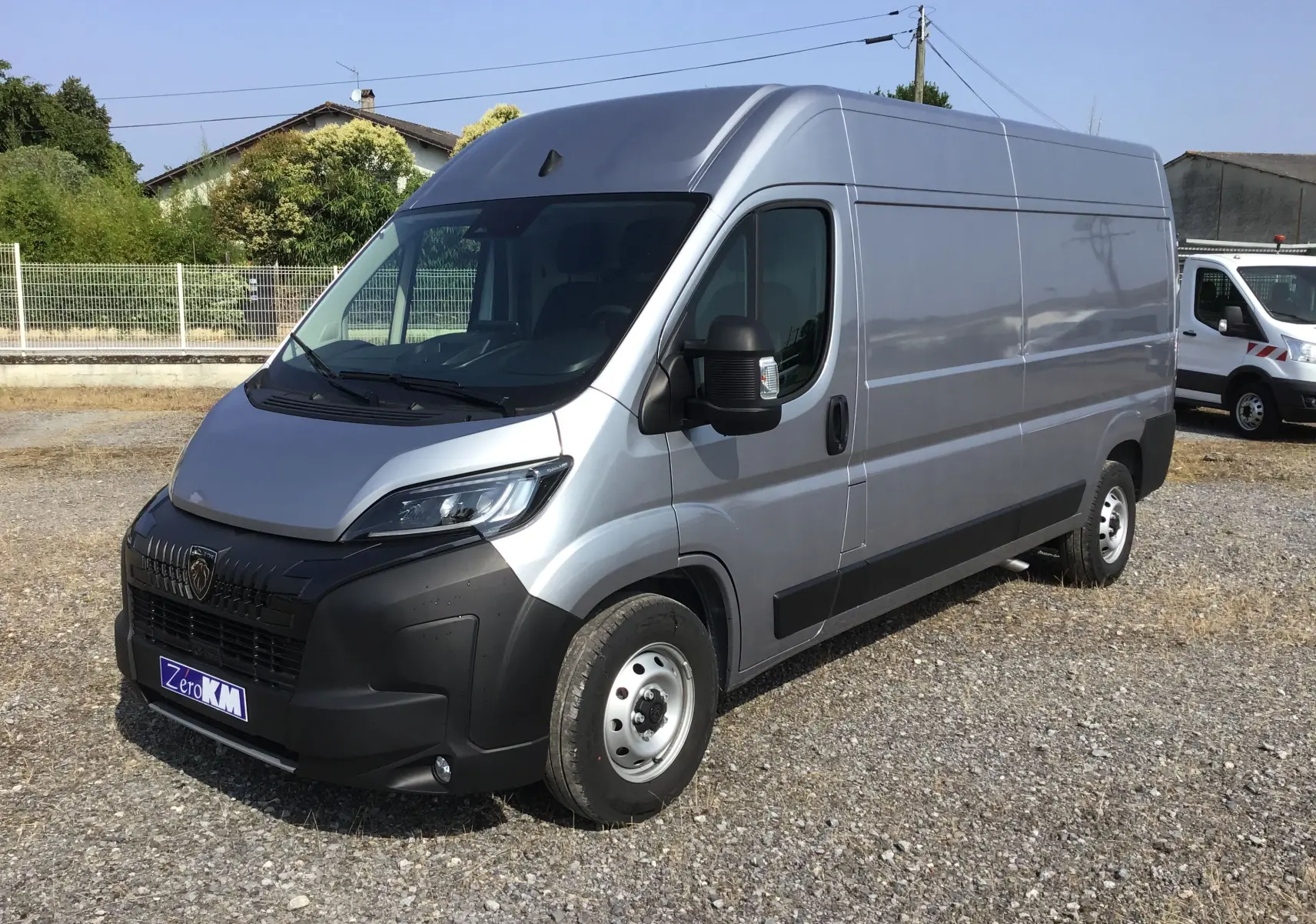 Vue 3/4 avant droit d'un Peugeot Boxer fourgon gris Artense avec calandre noire et projecteurs LED visibles.