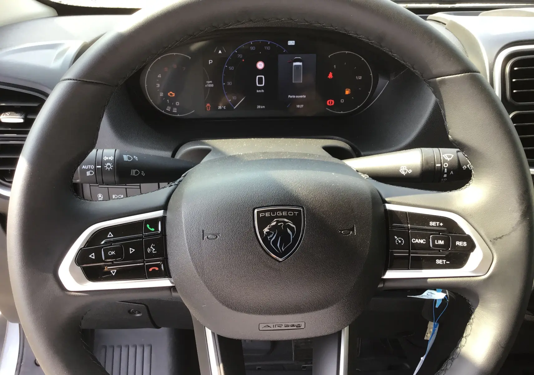 Vue rapprochée du volant Peugeot du Boxer Fourgon 2025 avec commandes intégrées et tableau de bord numérique.