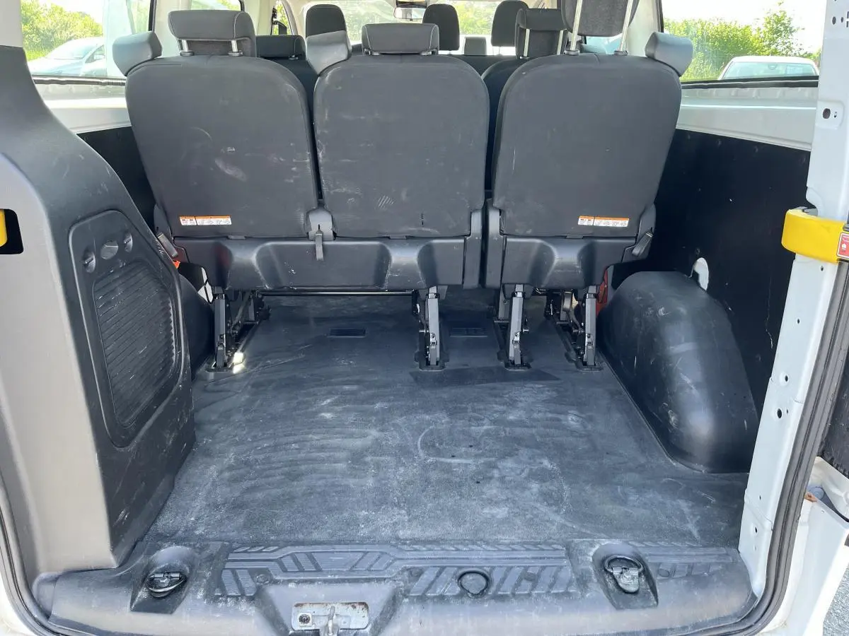 Vue arrière de l'habitacle du Ford Transit Custom blanc, montrant la banquette arrière et l'espace de chargement vide.