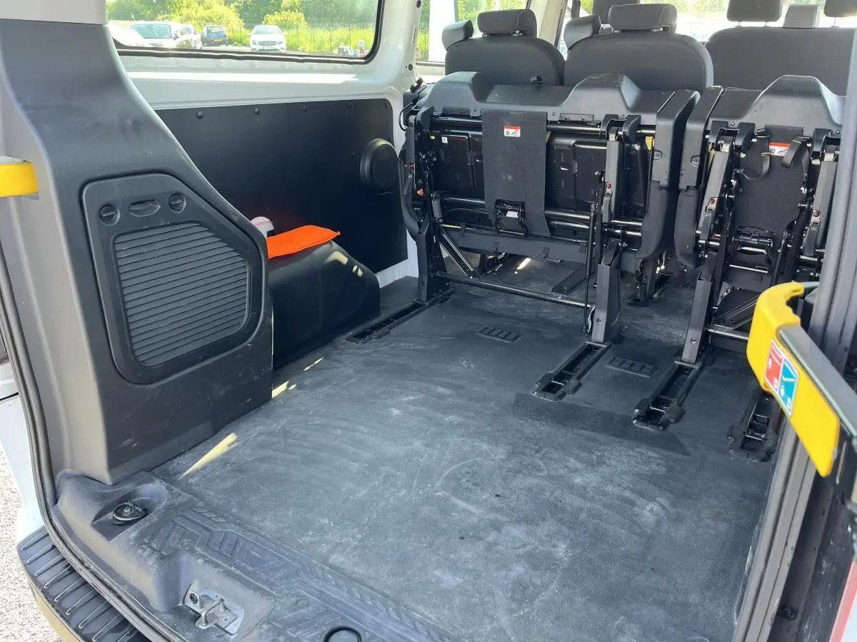Vue arrière intérieure du Ford Transit Custom blanc montrant l'espace de chargement et les sièges rabattus.