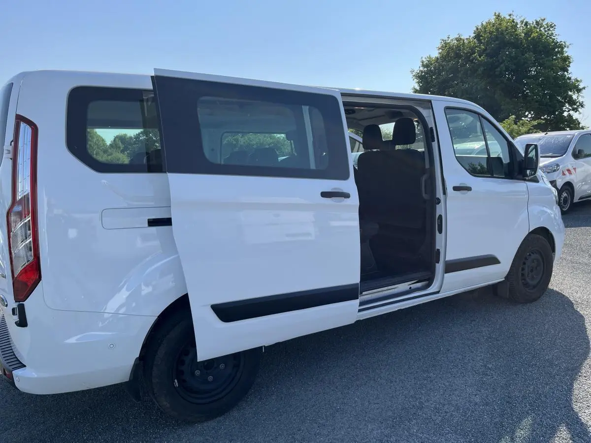 Ford Transit Custom Kombi blanc vu de côté droit avec porte coulissante ouverte montrant l'intérieur des sièges.