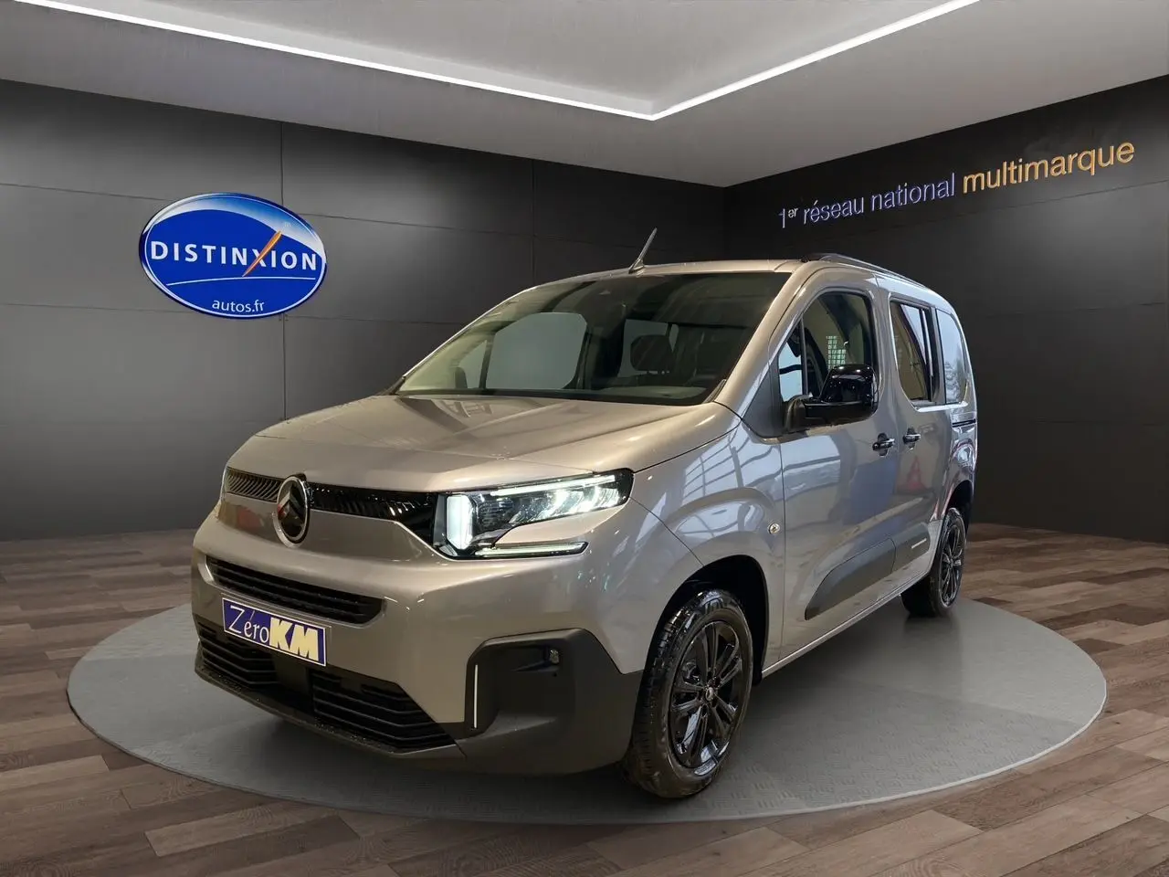 Citroën Berlingo 2025 gris Artense en 3/4 avant droit avec jantes noires et feux LED allumés.