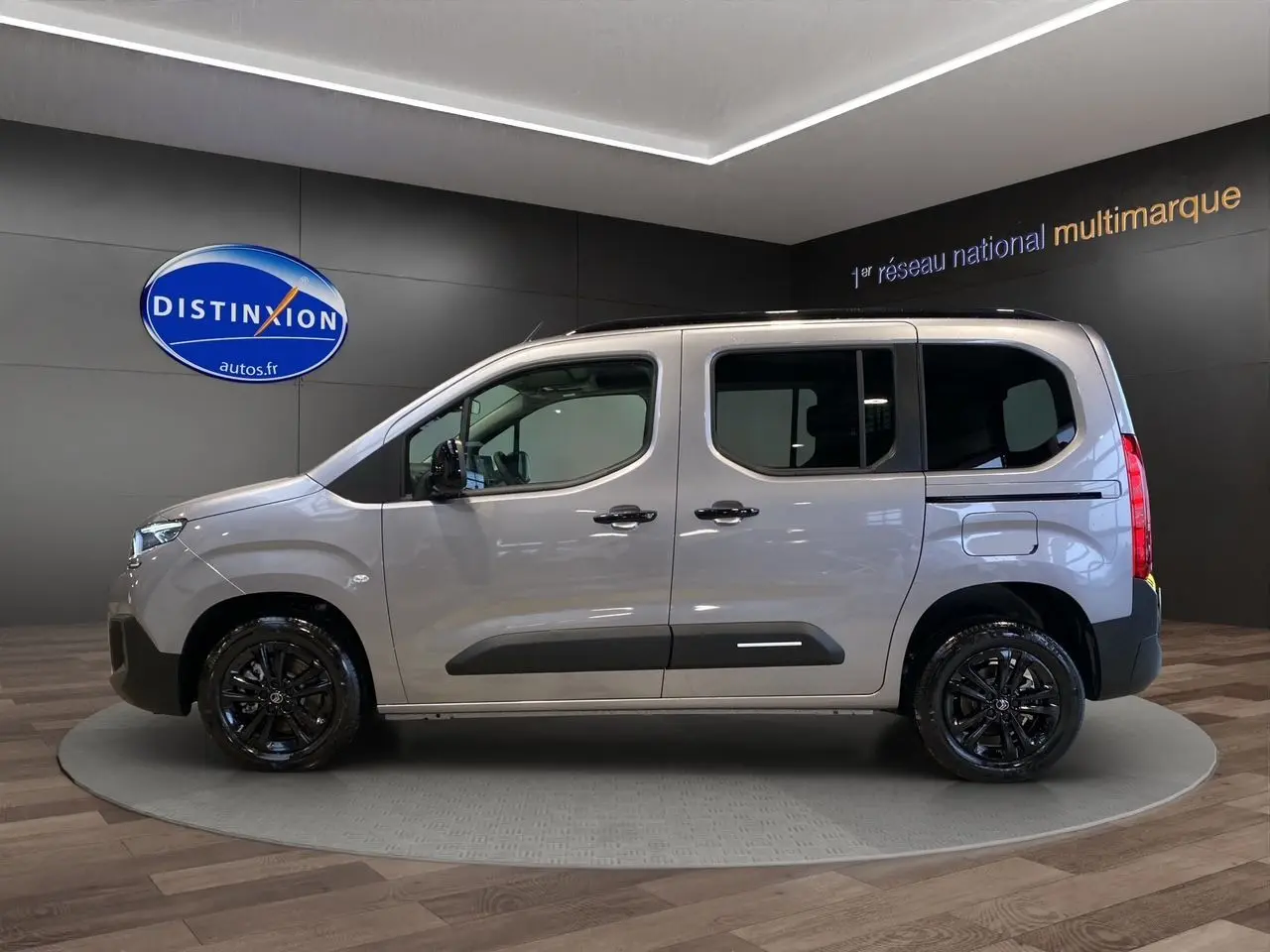 Profil latéral gauche du Citroën Berlingo gris Artense avec jantes noires brillantes en showroom.