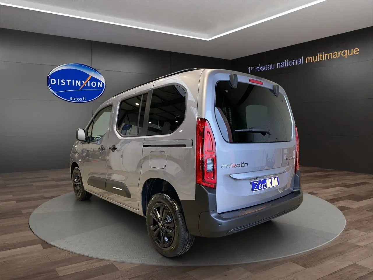 Vue 3/4 arrière droite d'un Citroën Berlingo gris Artense avec jantes noires dans un showroom.
