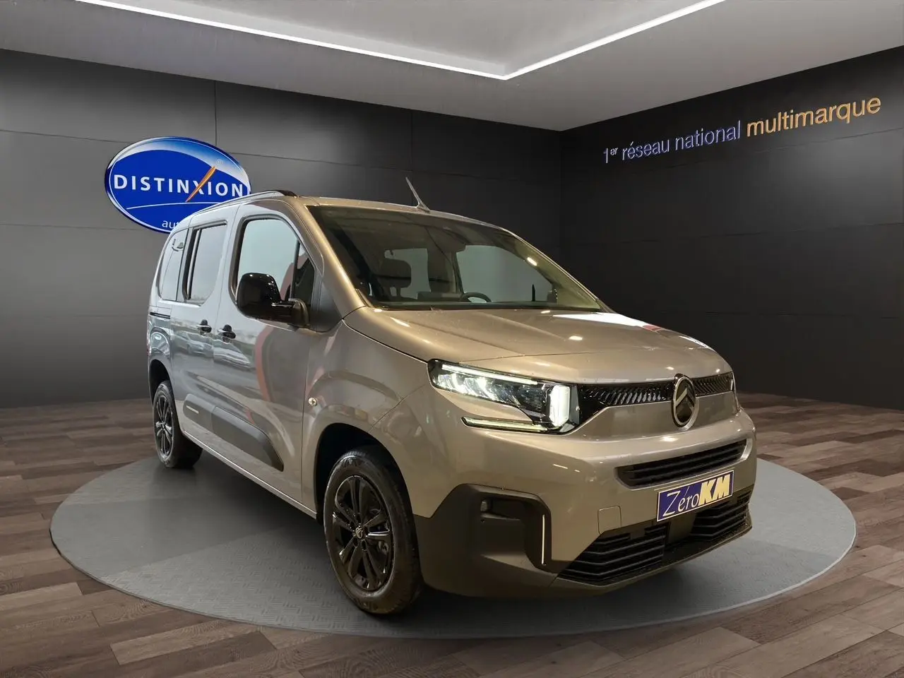 Citroën Berlingo Gris Artense en 3/4 avant droit avec jantes noires et caméra de recul visible en showroom.