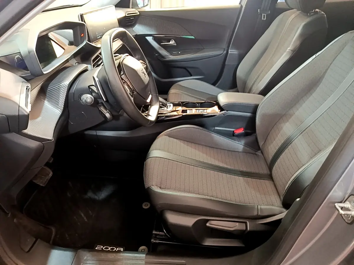 Intérieur avant droit du Peugeot 2008 gris clair 2021, sièges tissu, volant cuir et tableau de bord numérique.