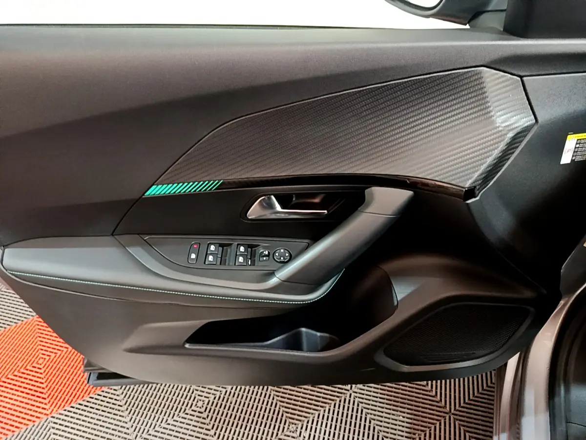 Intérieur côté conducteur du Peugeot 2008 gris clair 2021, avec panneau de porte noir et insert effet carbone.