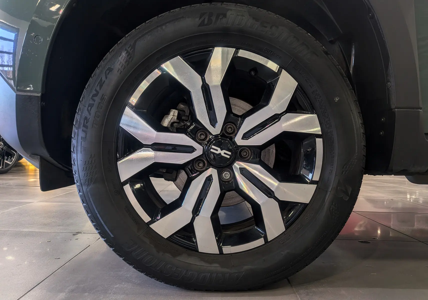 Gros plan sur la roue avant gauche du Dacia Duster 2023 Kaki Lichen avec jante alliage bi-ton noir et argent.