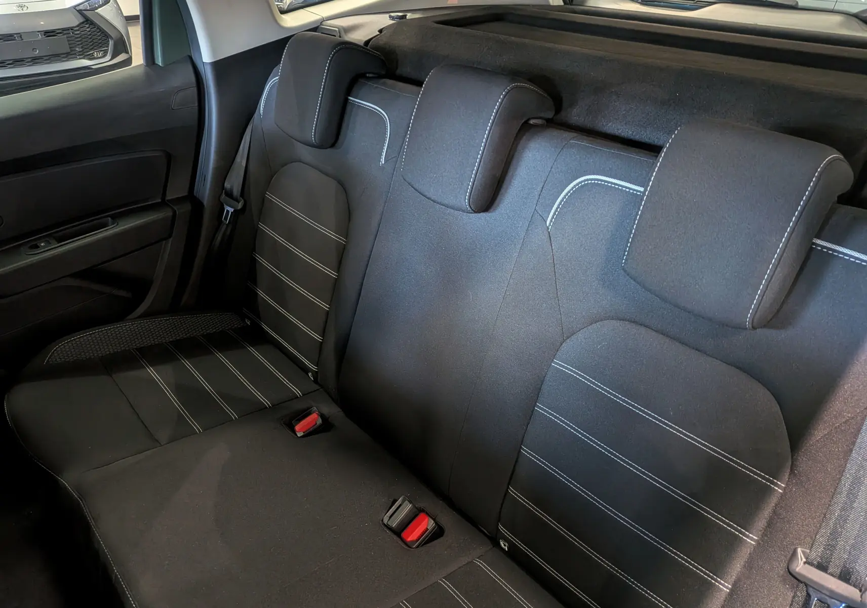 Vue intérieure sur la banquette arrière en tissu noir avec surpiqûres blanches du Dacia Duster 2023.